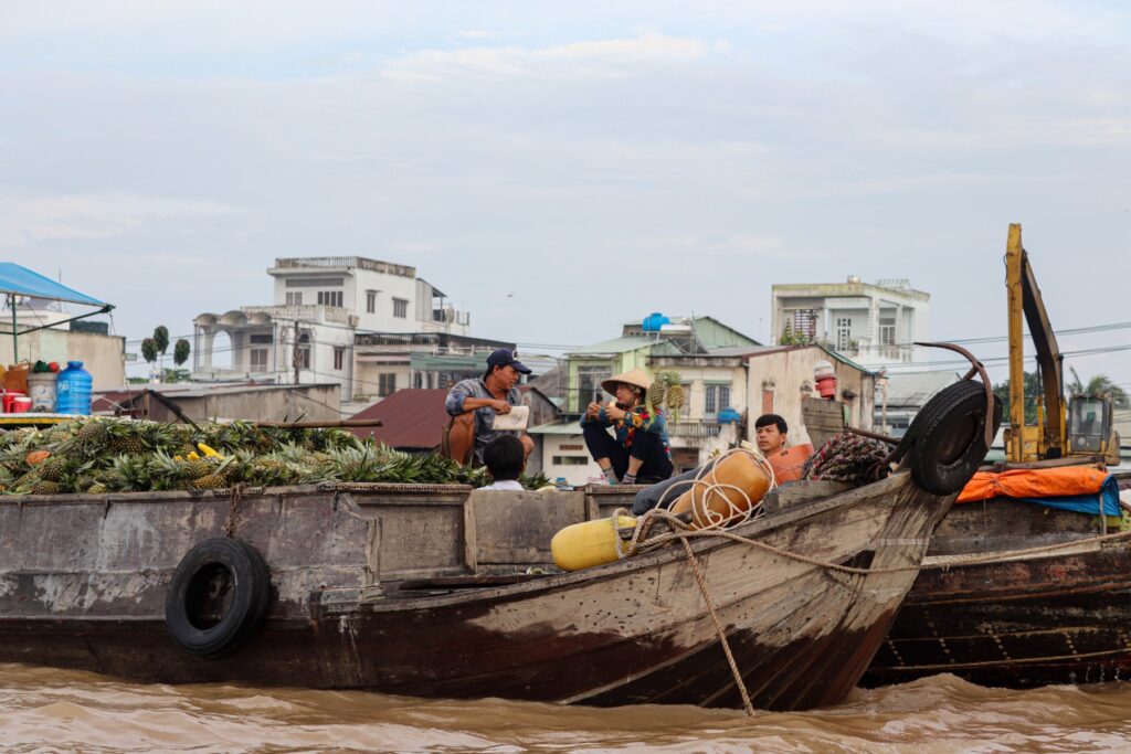 A group of people sitting on top of a wooden boat. Photo by Nathan Cima - Top Cities in South Vietnam: The Ultimate Travel Guide