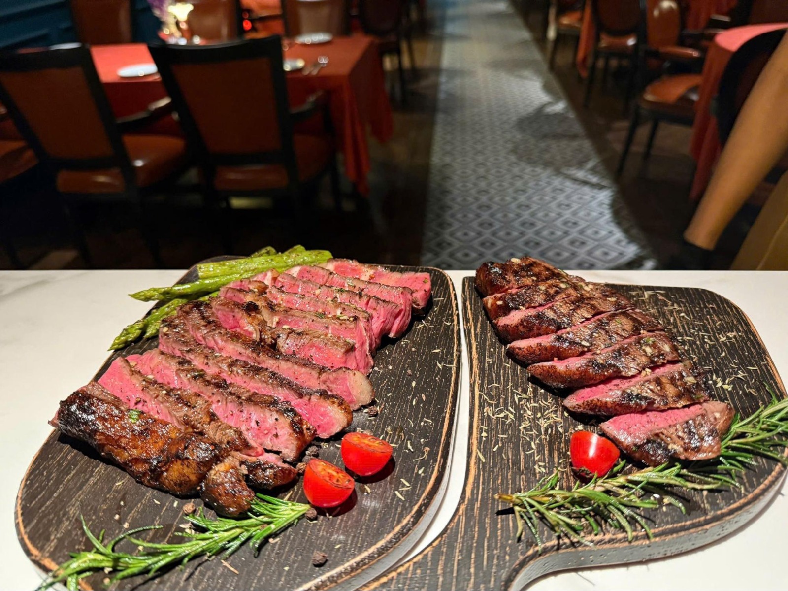 Juicy sliced steaks on wooden boards with herbs and vegetables at El Toro restaurant in Thao Dien.