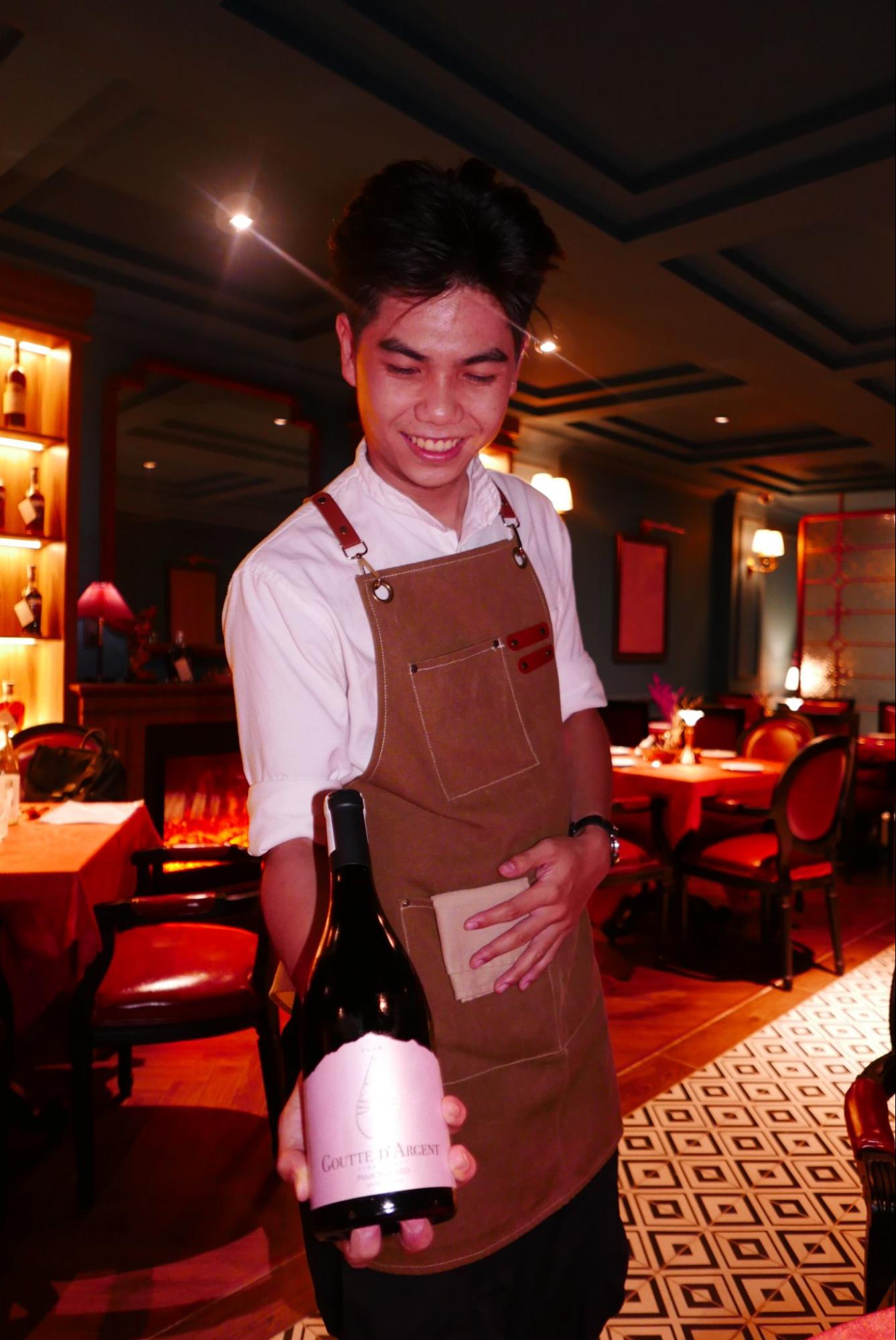 El Toro waitstaff holding a bottle of wine for tableside service in Thao Dien restaurant.